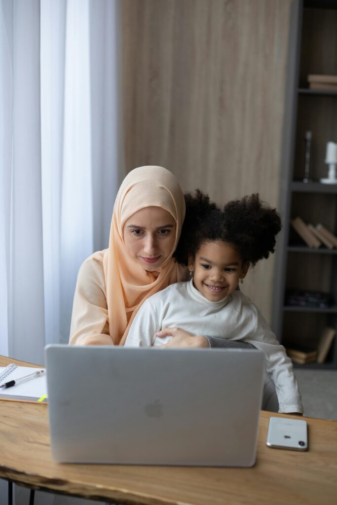 A mother and daughter enjoy quality time together using a laptop at home.